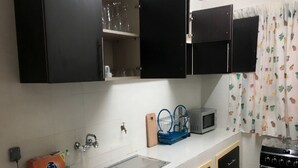 A kitchen with black cabinets, a stainless steel sink, a microwave, and a stove.