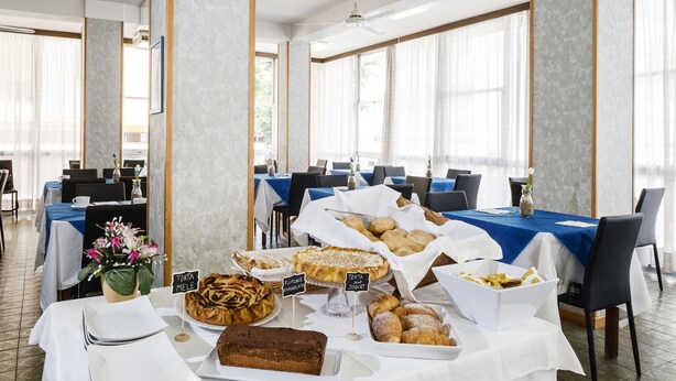 A dining area with tables set for breakfast, featuring various pastries and desserts. - Hotel Belmar (Rimini)