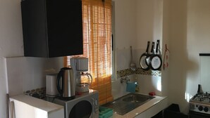 Een kleine keuken met een magnetron, koffiezetapparaat en fornuis.