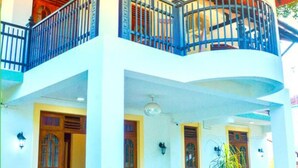 A two-story building with a balcony, wooden doors, and a tiled patio area with chairs. - Marathona Tourist Resort - Anuradhapura (Anuradhapura)