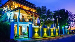 A two-story building with a balcony, a covered porch, and a well-lit entrance. - Marathona Tourist Resort - Anuradhapura (Anuradhapura)