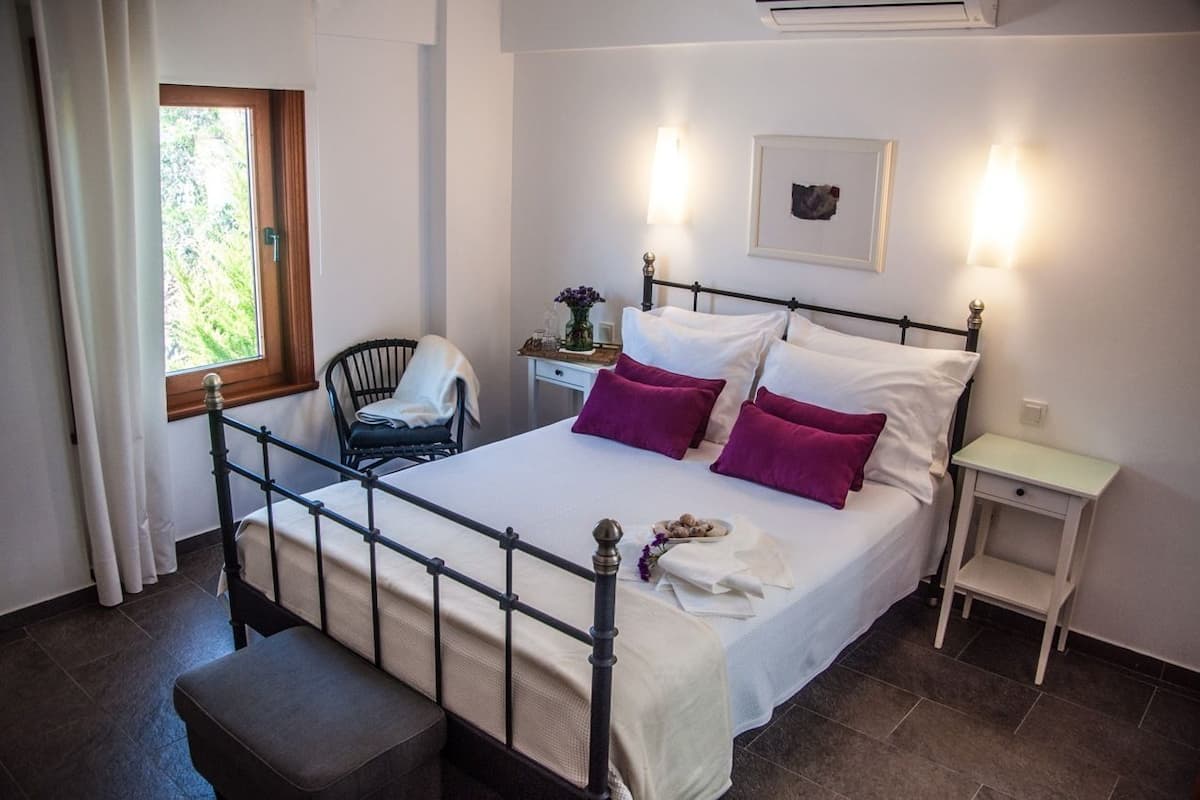 A neatly arranged bedroom with a bed, bedside tables, a chair, and a window.