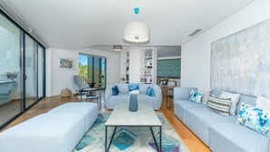 A modern living room with a sofa set, a coffee table, and a dining area in the background.