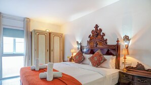 Une chambre d’hôtel avec un grand lit, une armoire, une table de chevet avec des lampes et une fenêtre avec des rideaux.