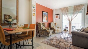 Un coin repas avec une table dressée pour quatre personnes, deux fauteuils, un canapé et un tapis à motifs.
