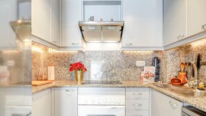 Une cuisine moderne avec des armoires blanches, une hotte de cuisinière en acier inoxydable et un comptoir en granit.