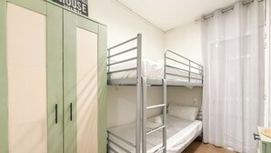 Quarto com beliche, guarda-roupa e cortina.