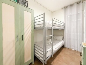 Une chambre avec un lit superposé, une armoire et un rideau.