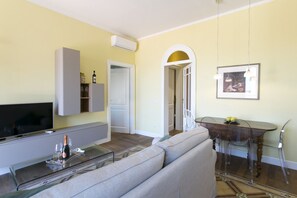 Un soggiorno con divano, televisore e tavolino in vetro. C'è anche un'area pranzo con tavolo e sedie.