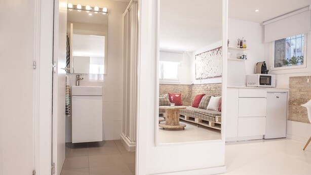 A modern kitchen with white cabinets, a microwave, and a coffee machine.