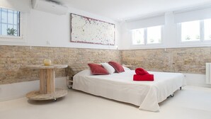 A bedroom with a large bed, a brick wall, and a large window.