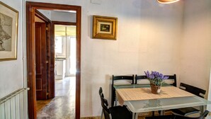 Un comedor con una mesa, sillas, un florero con flores y un cuadro en la pared.