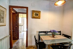 A dining area with a table, chairs, a vase with flowers, and a framed picture on the wall. - The Rose by Hello Homes Sitges (Sitges)