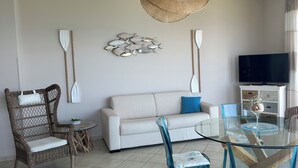 A living room with a sofa, a dining table with chairs, a TV, and a hanging light fixture. - Sea view villa with pool near Tropea (Zambrone)