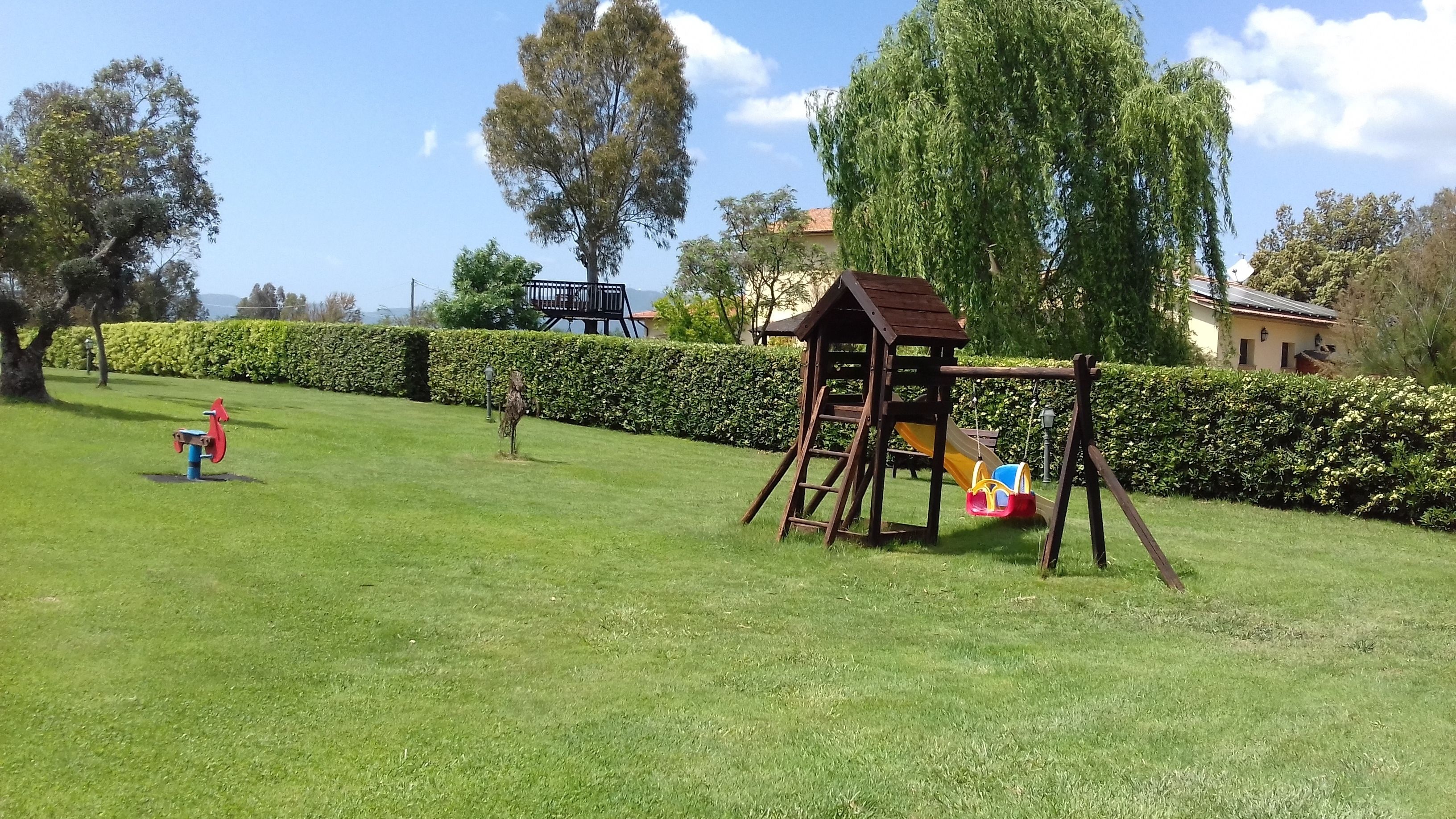 A grassy park with playground equipment including a swing set and a slide.