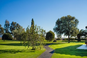 Un sendero pavimentado en un parque con césped verde y árboles.