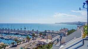 Un port de plaisance avec des bateaux, une piscine et une vue sur la mer et le paysage lointain.