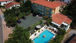 A hotel with a swimming pool, a parking area, and a red-tiled roof. - Hôtel Aquitaine (Capbreton)