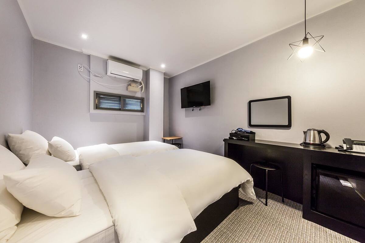 Camera d'albergo moderna con un letto grande, una scrivania con bollitore, una TV a schermo piatto e un camino.
