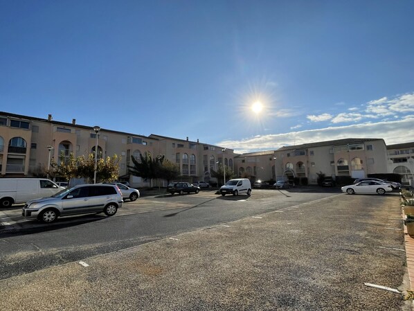 A parking lot with several cars and a building with multiple windows and balconies. - Cozy 2-Room Apartment 300m from Beach with Parking in Sète (Sète)