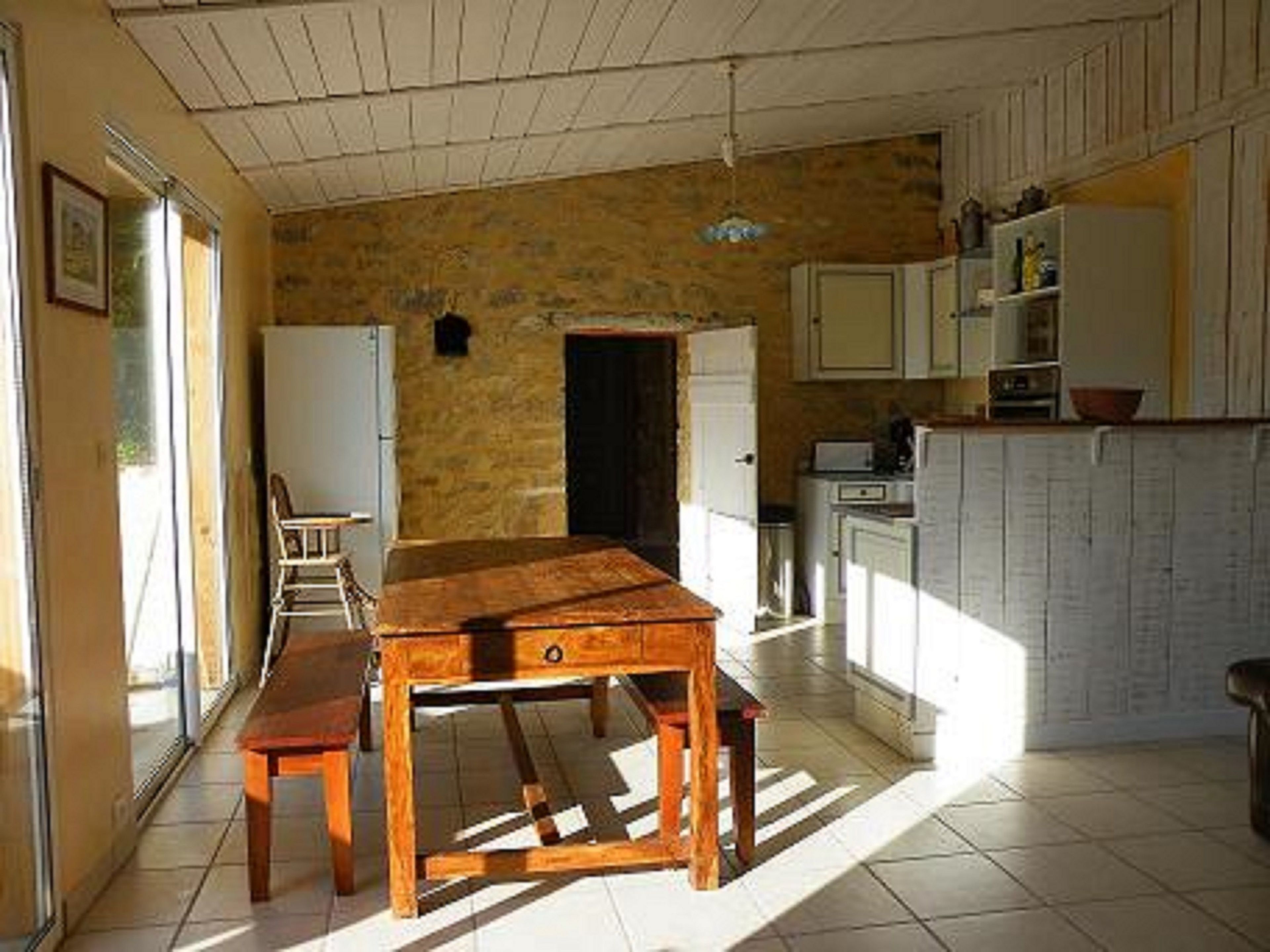 Una cocina con una mesa y sillas de madera, un refrigerador y armarios.