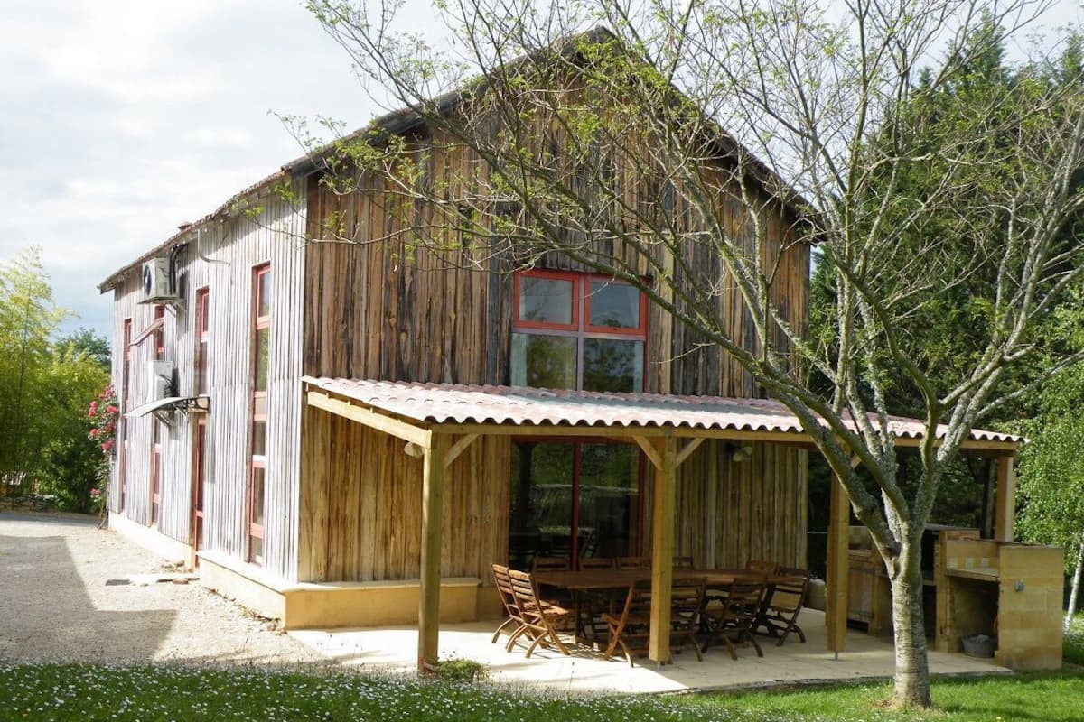 A rustic wooden house with a covered patio and outdoor seating area.