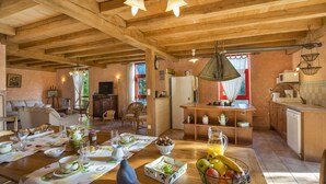 A spacious living area with a wooden ceiling, a dining table set with breakfast items, and a kitchen area with a refrigerator and cabinets. - Le Domaine de Pecany (Le Buisson-de-Cadouin)