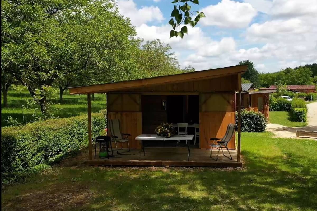 A wooden cabin with a covered porch, a table with chairs, and a garden area.