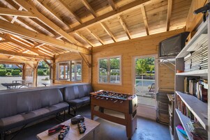 Um espaço interior aconchegante com uma mesa de futebol de mesa, um sofá e uma televisão.