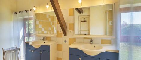 Un baño con dos lavamanos, vigas de madera y un ventanal grande.