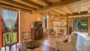 A cozy living room with a sofa, chairs, a television, and a dining area with a table and chairs. - Le Domaine de Pecany (Le Buisson-de-Cadouin)
