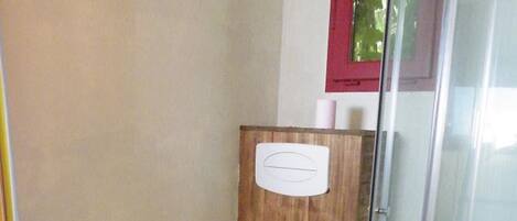 Een badkamer met een wand van houten panelen, een wit toilet, een douchecabine van glas en een witte wastafel.