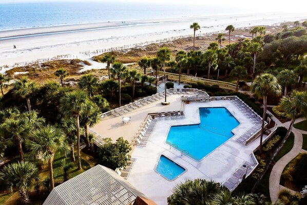 A resort with a large pool, palm trees, and a beach view.