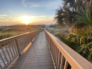 A wooden boardwalk leading to a beach with a sunset in the background. - 4BR Palmetto Dunes / Steps to Beach +Oceanfront Pool / Lagoon view/Captains Cove (Hilton Head Island)