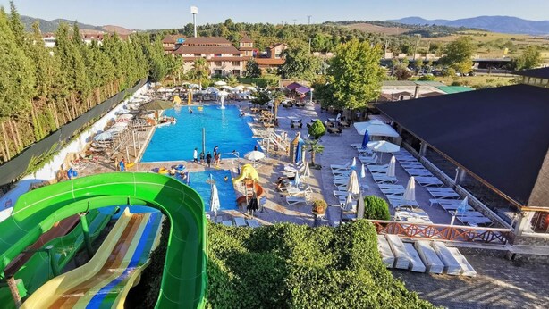 Un complejo turístico con piscina, tumbonas y tobogán de agua.
