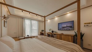 A modern hotel room with a large bed, a desk, a chair, a TV, and a window with curtains. - Hangzhou West Lake Yueshang Yunshe Boutique Homestay (Hangzhou)