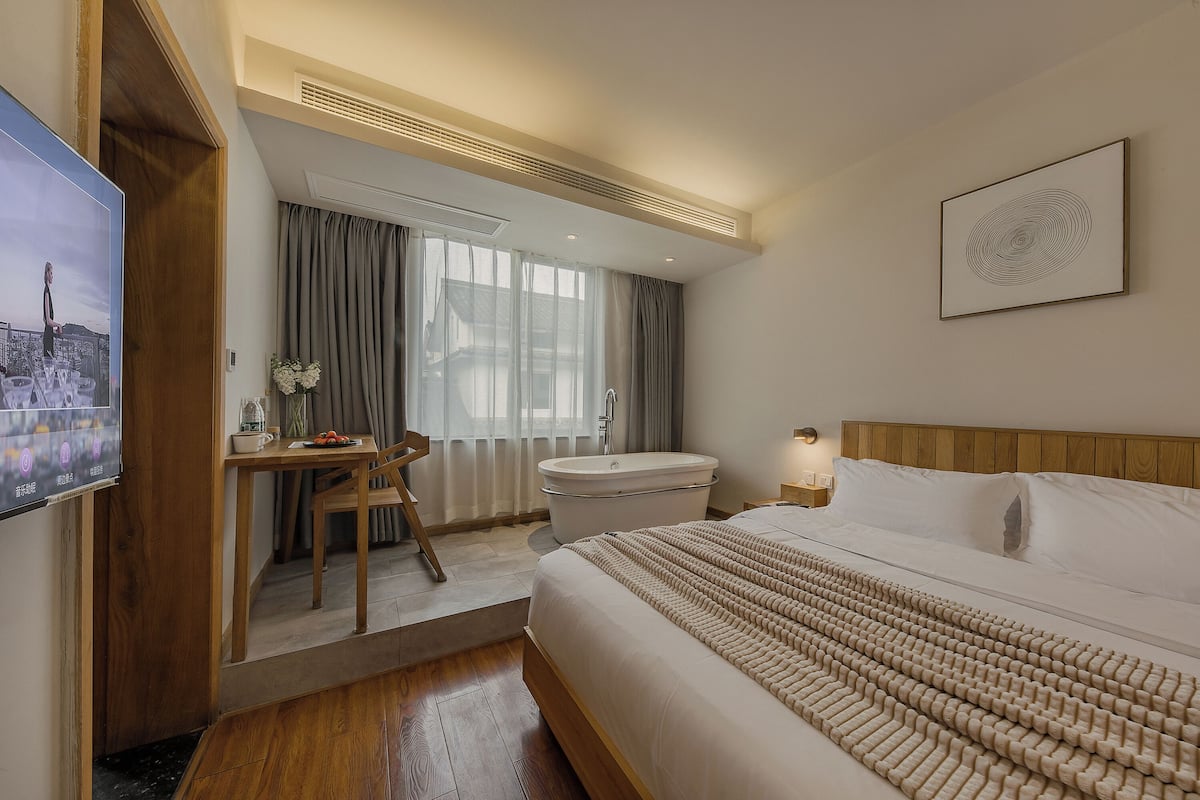 Ein Hotelzimmer mit einem Bett, einem Schreibtisch, einem Stuhl, einer Badewanne und einem Fernseher.