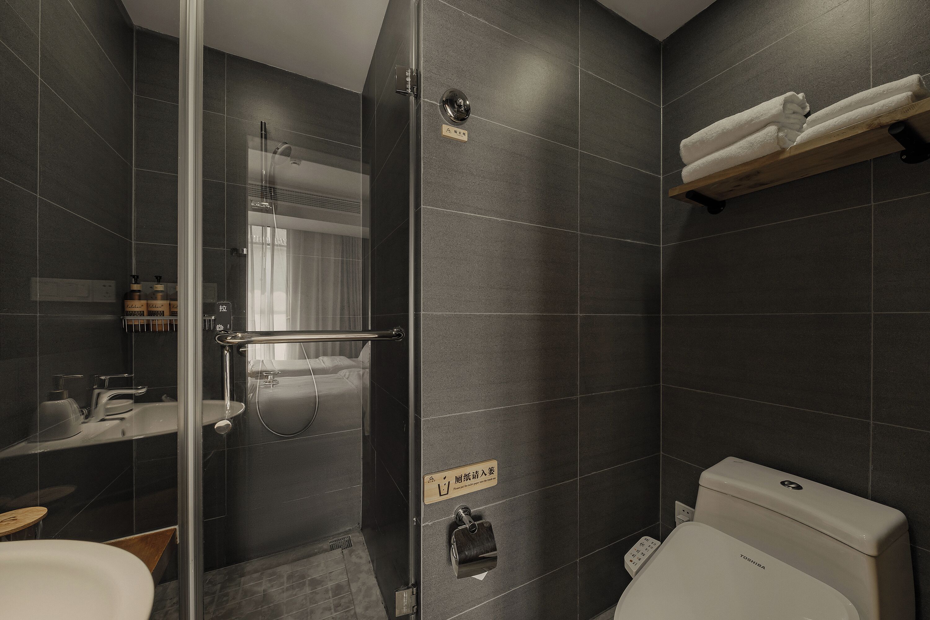 Une salle de bain moderne avec une douche à parois de verre, des toilettes et un porte-serviettes.
