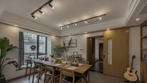 A dining area with a wooden table and chairs, a potted plant, and a guitar. - Hangzhou West Lake Yueshang Yunshe Boutique Homestay (Hangzhou)