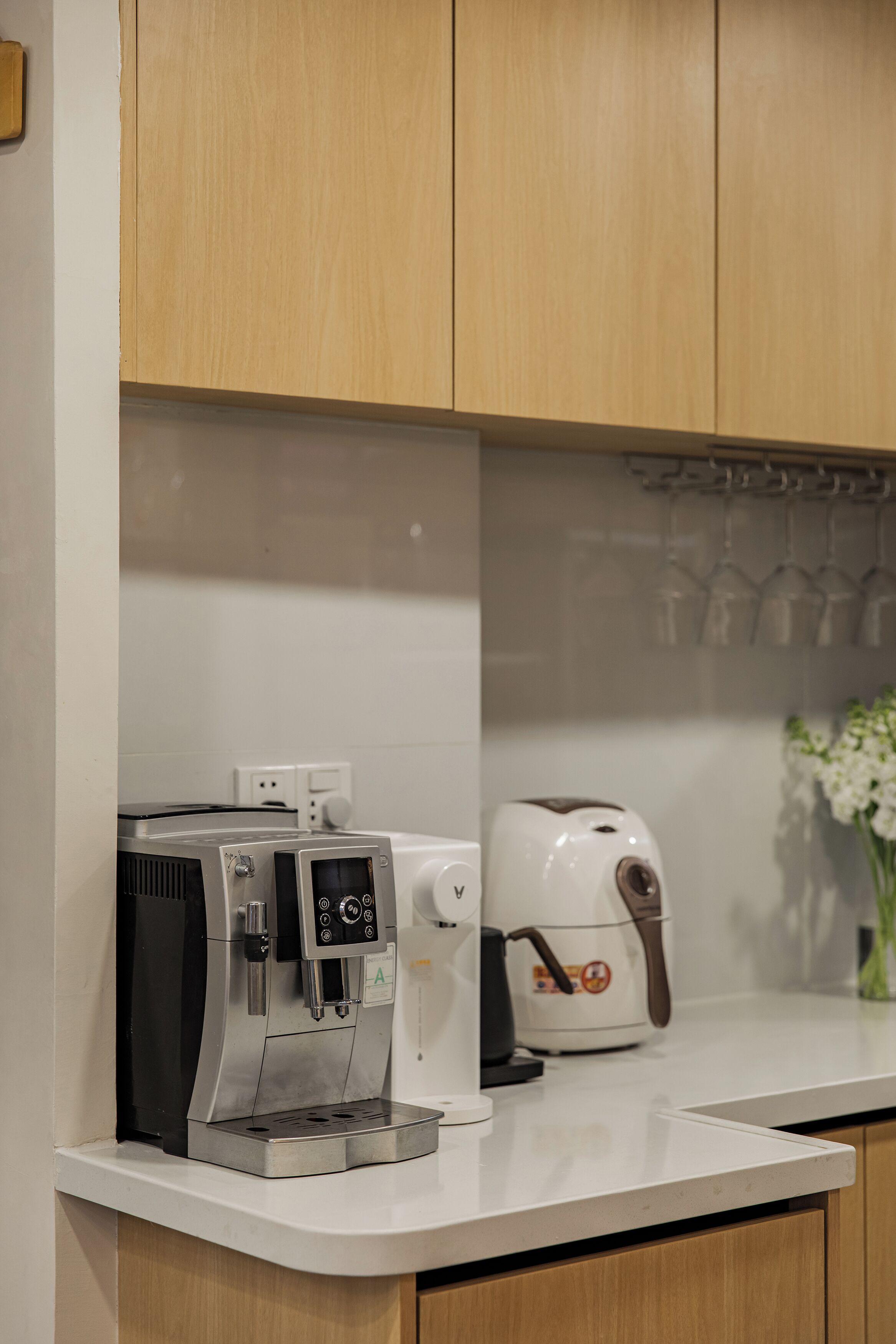 Een keuken met een koffiezetapparaat, waterkoker en broodrooster op het aanrecht.