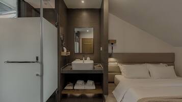 A modern hotel room with a shower, sink, and bed.