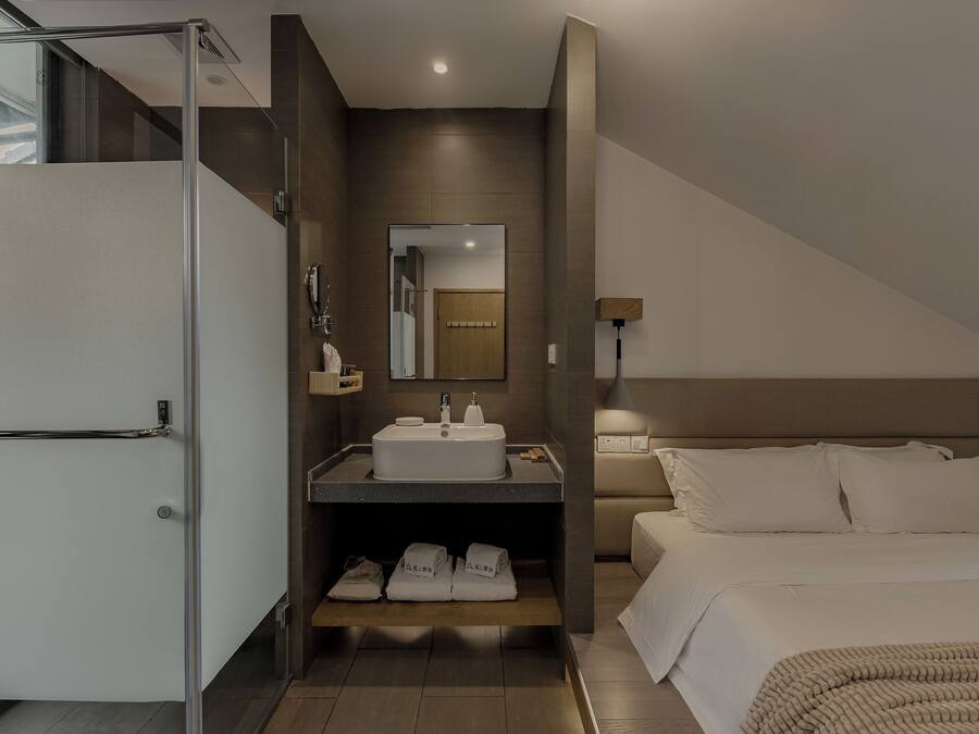 A modern hotel room with a shower, sink, and bed.