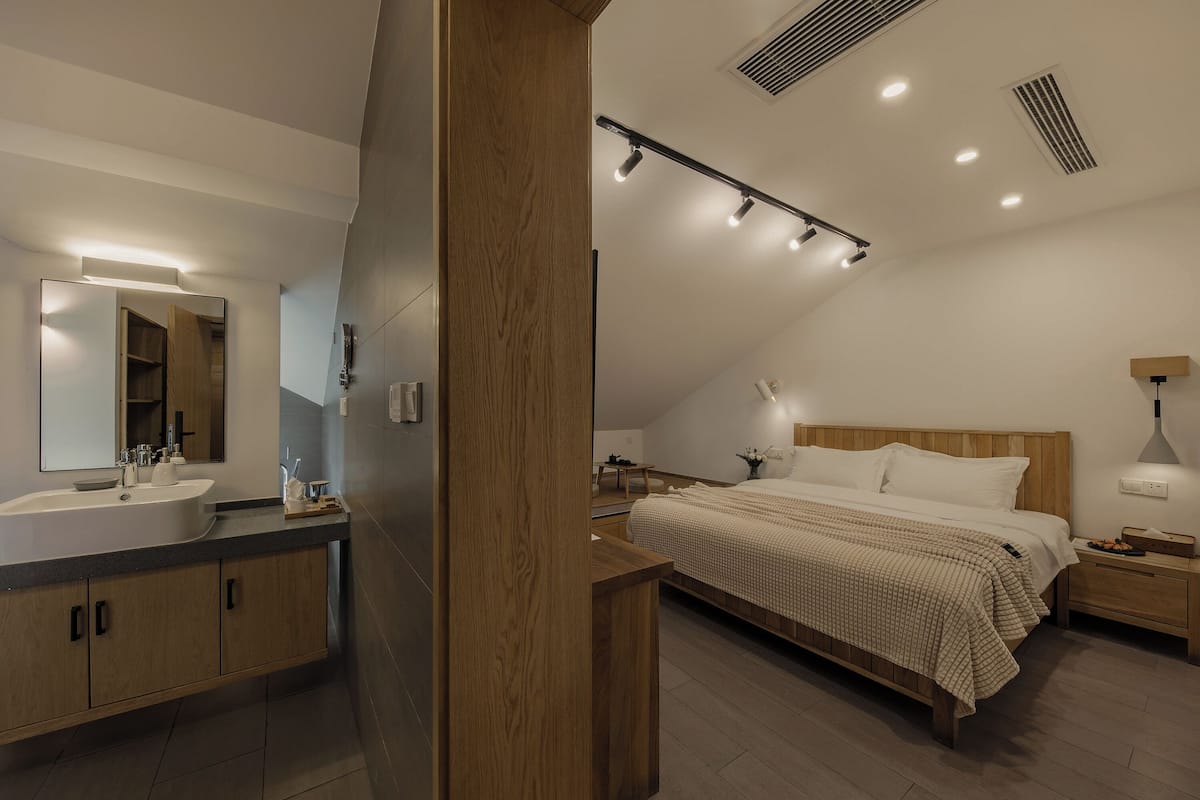 Ein modernes Schlafzimmer mit einem großen Bett, Nachttischen, einer Nachttischlampe und einem Holzkopfende.