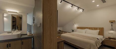 A modern bedroom with a large bed, bedside tables, a nightstand, a bedside lamp, and a wooden headboard.