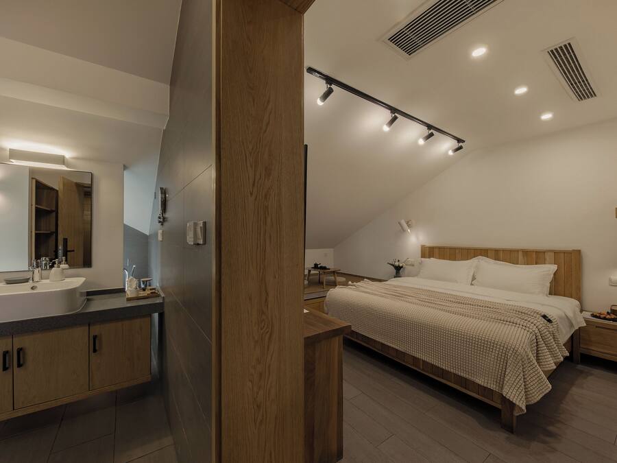 Ein modernes Schlafzimmer mit einem großen Bett, Nachttischen, einer Nachttischlampe und einem Holzkopfende.