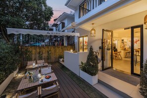 A modern outdoor dining area with a wooden table and chairs, surrounded by potted plants and a decorative fence. - Hangzhou West Lake Yueshang Yunshe Boutique Homestay (Hangzhou)