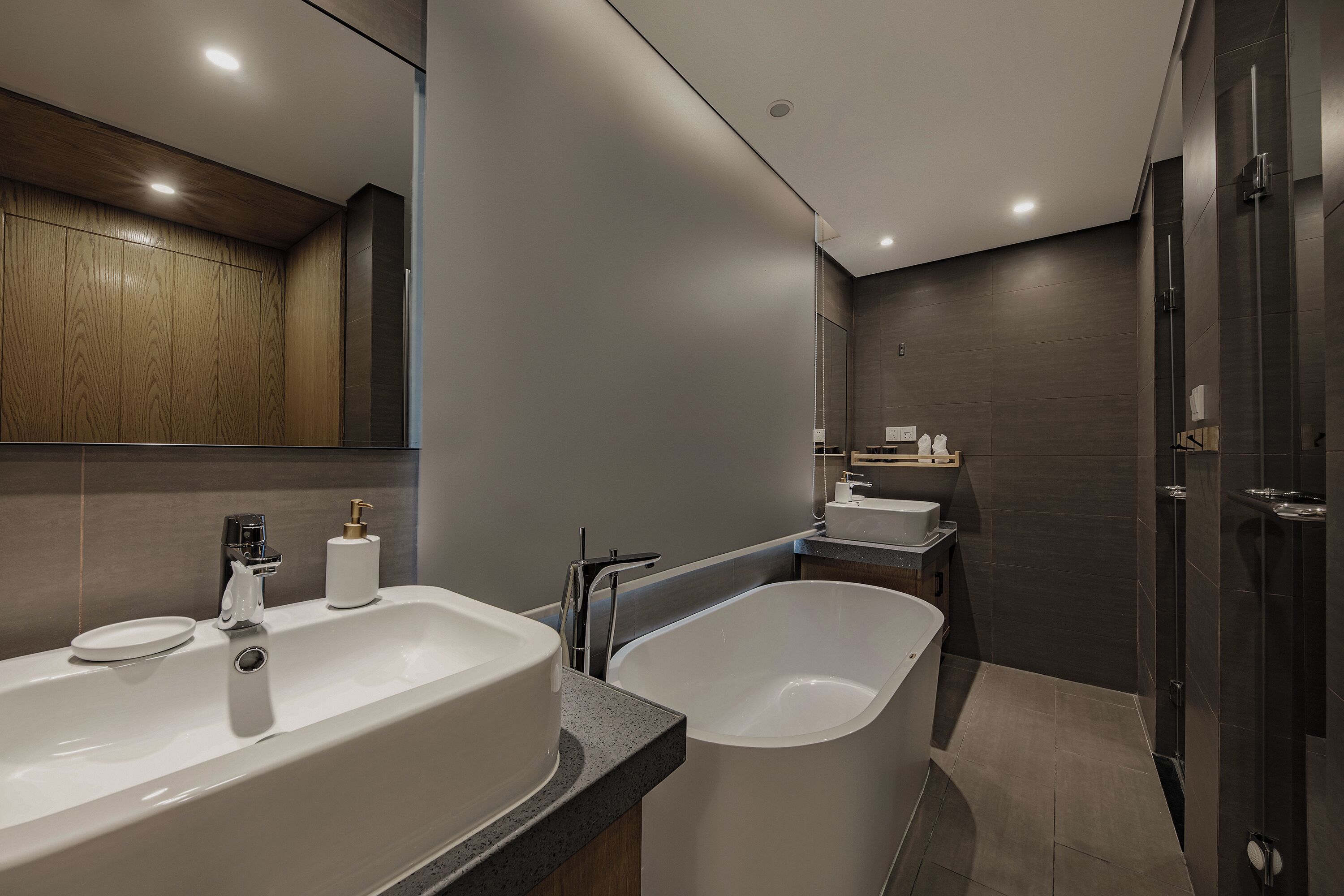 A modern bathroom with a large bathtub, a separate sink, and a shower area.