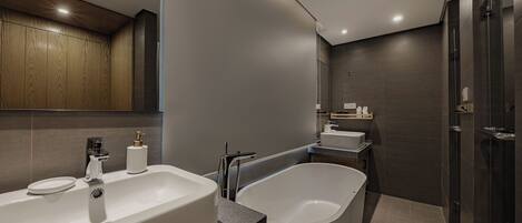 A modern bathroom with a large bathtub, a separate sink, and a shower area.