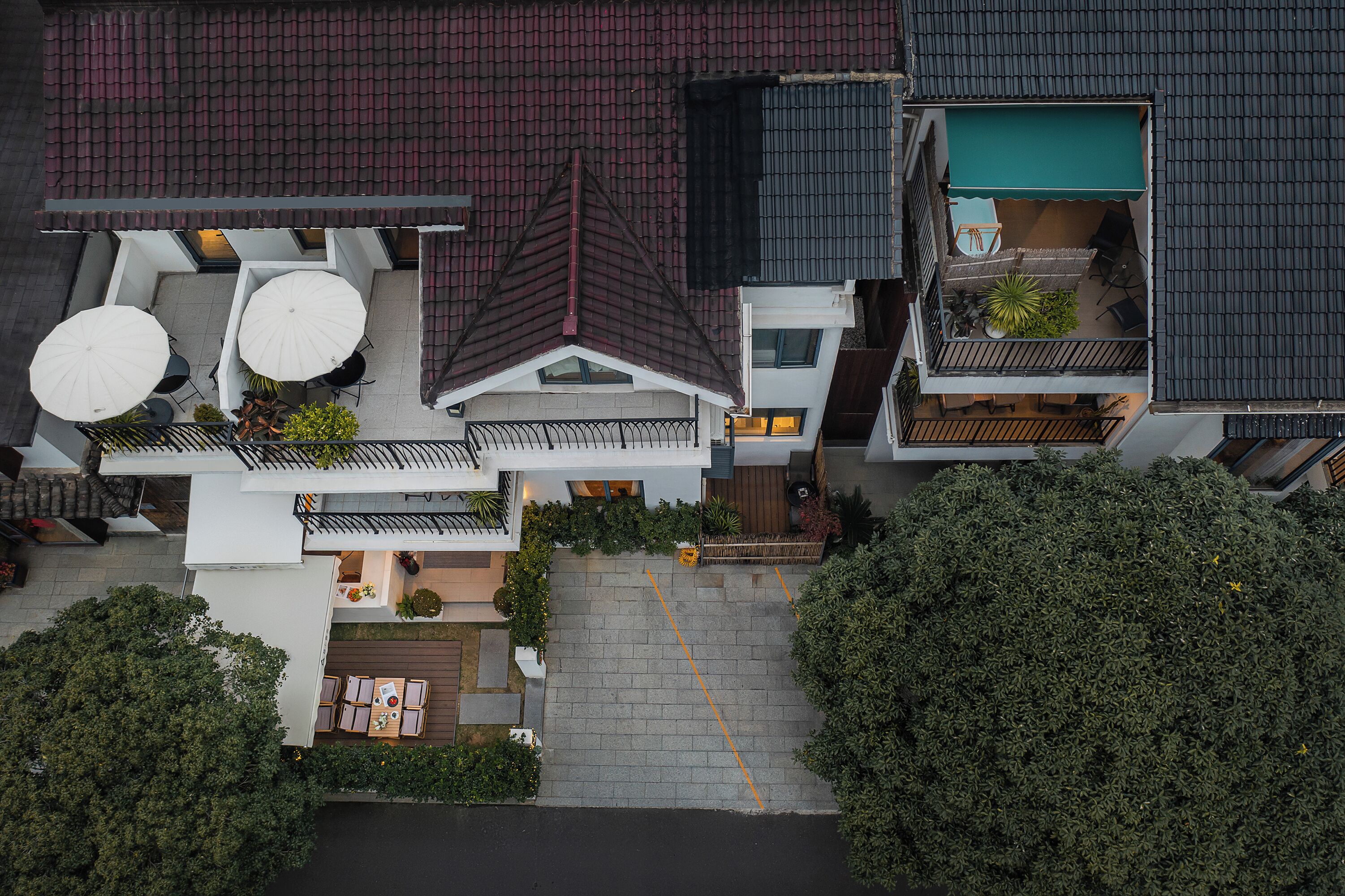 A multi-story residential building with a rooftop terrace, a covered outdoor seating area, and a visible garden.