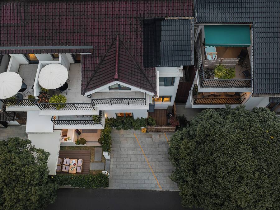 A multi-story residential building with a rooftop terrace, a covered outdoor seating area, and a visible garden.